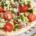 Close-up of a loaded hummus pita with colorful toppings