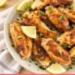 Dry Rub Chicken Wings with golden spice-coated skin, lemon wedges and herbs on an ivory platter, Recipnest