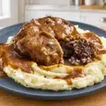 Salisbury steak with brown gravy and mashed potatoes on a slate-blue plate