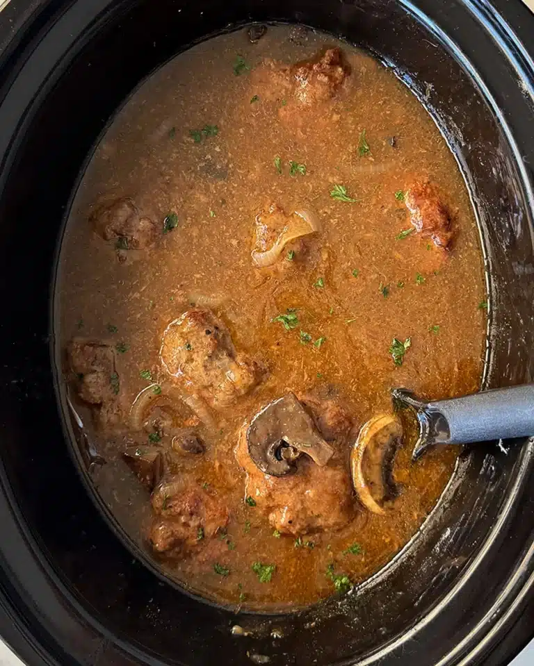 Cooked Salisbury Steak with gravy in a black slow cooker